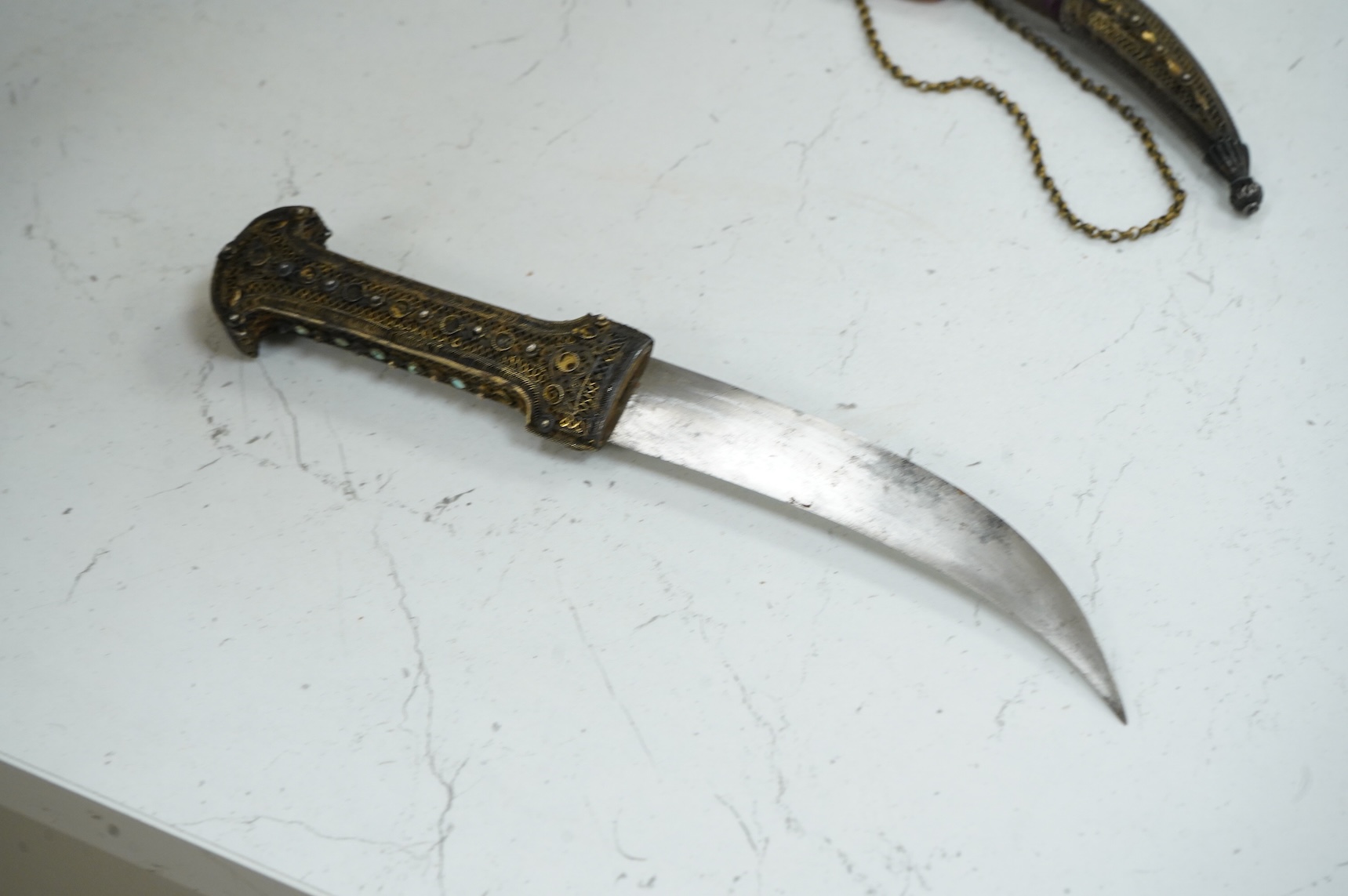 A Late 19th century Hungarian dagger, the hilt and sheath mounts made from filigree gilt silver wire applied with cabochon turquoise and red stones (some missing), blade 13.5cm